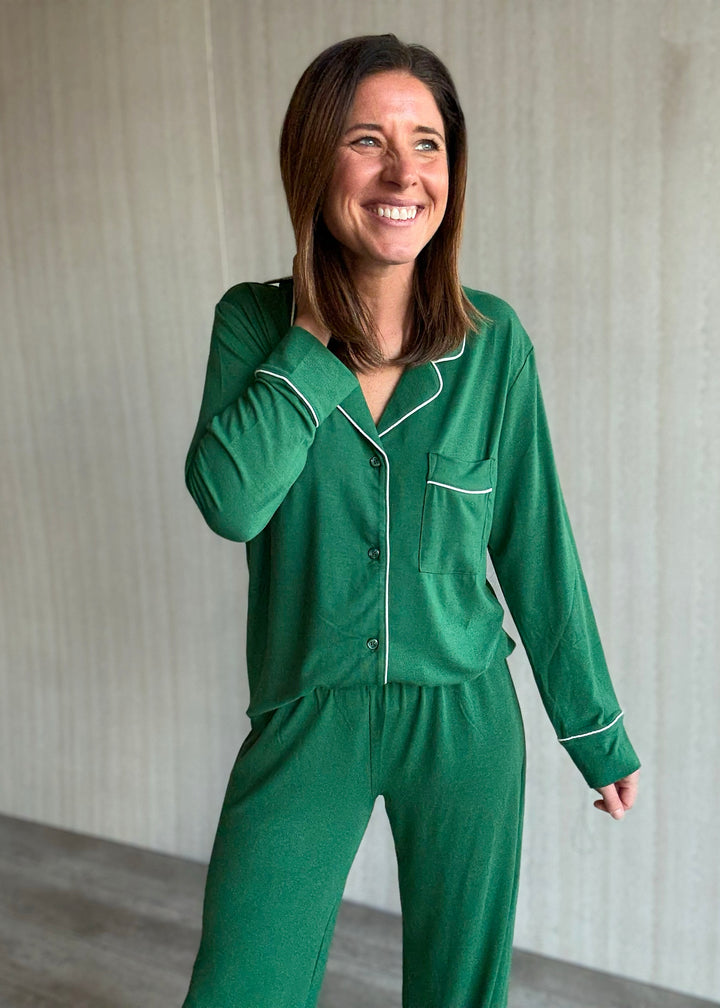 Woman wearing green pajamas with white piping against a neutral background