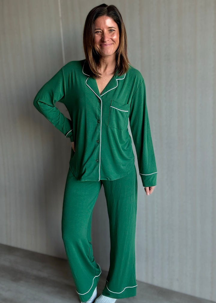 Woman wearing a green pajama set with white piping against a neutral background