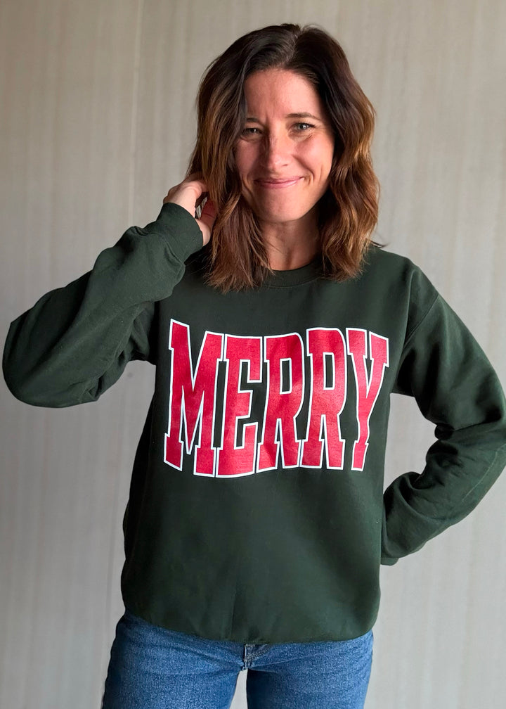 Person wearing a green sweatshirt with 'MERRY' in red letters against a plain background