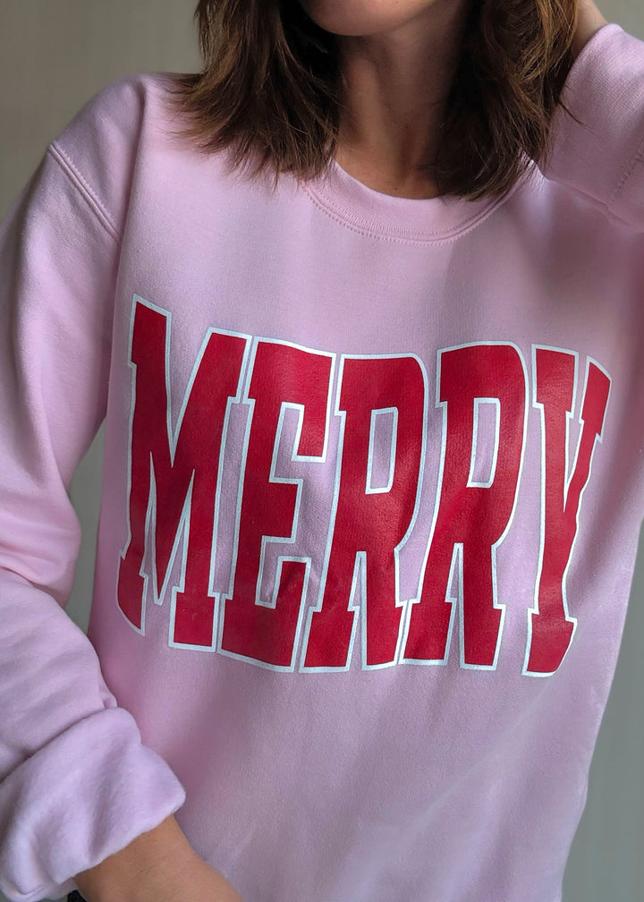 Pink sweatshirt with red and white text on a plain background