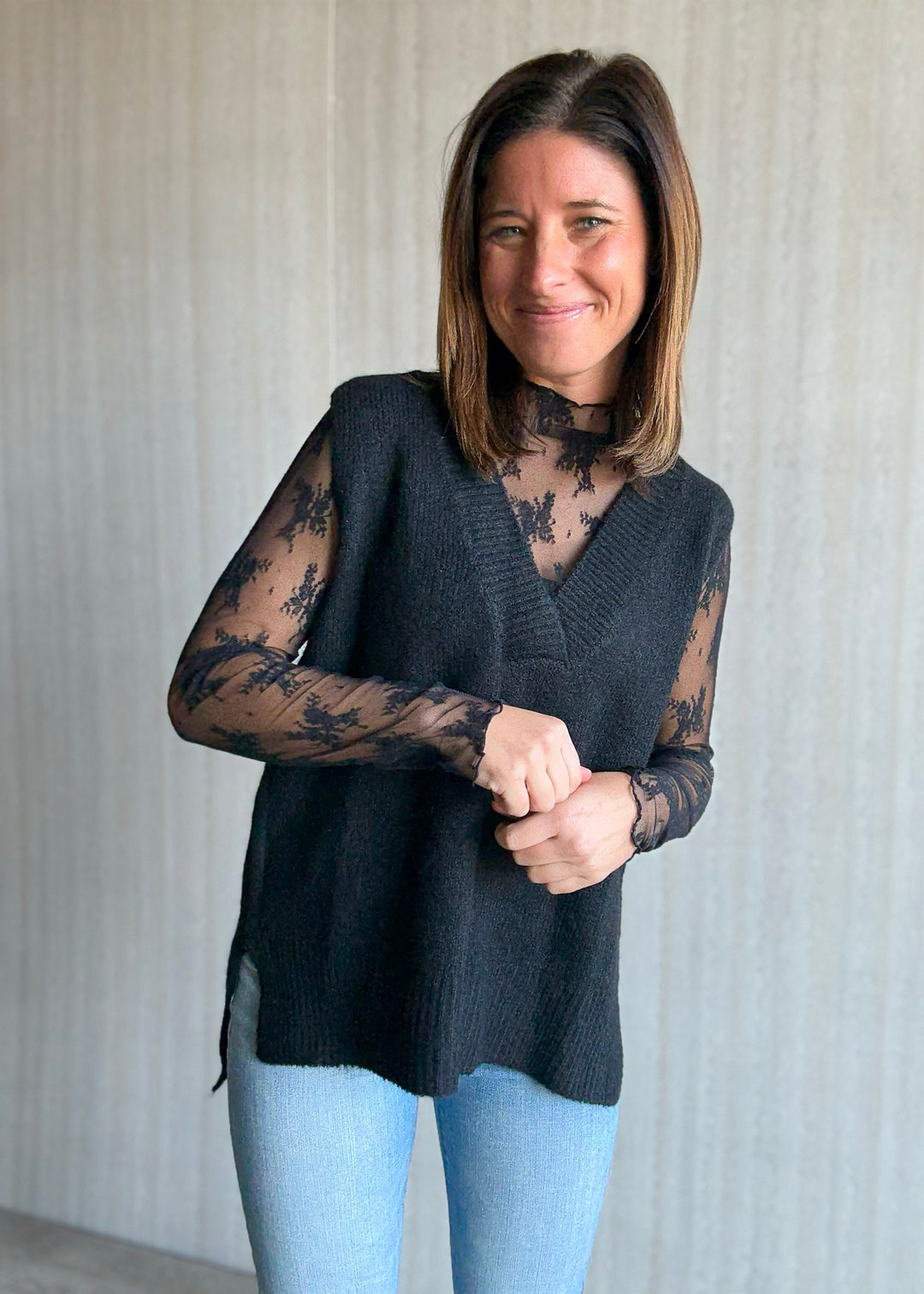 Women's Oversized Black Sweater Vest w/V-neck line paired over a sheer black lace long sleeve top.