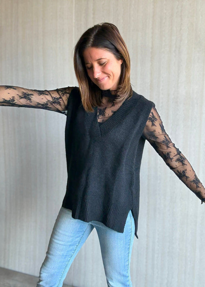 Women's Oversized Black Sweater Vest w/V-neck line paired over a sheer black lace long sleeve top.