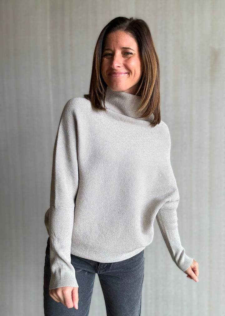 Woman wearing a light gray sweater against a plain background