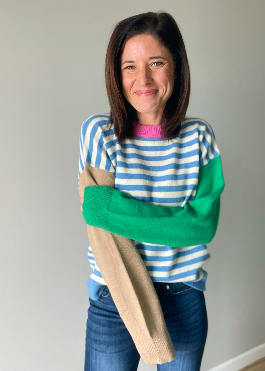 Women's color block sweater with blue stripes, pink collar, and green and tan sleeves.