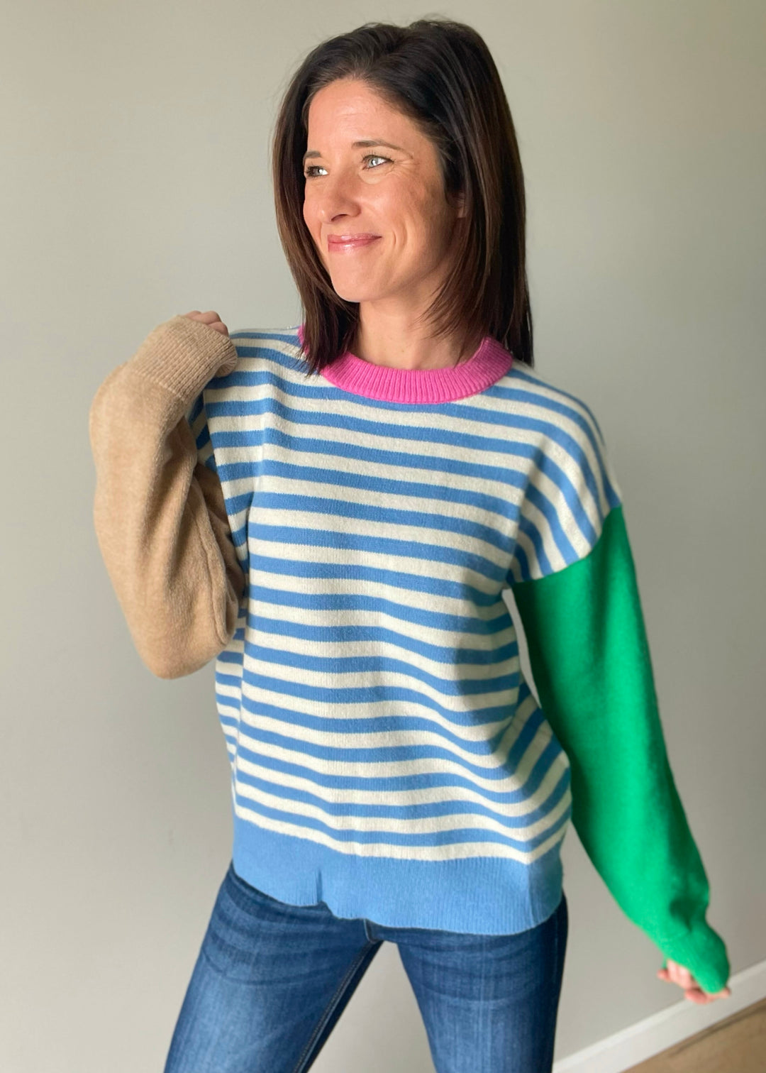 Women's color block sweater with blue stripes, pink collar, and green and tan sleeves.