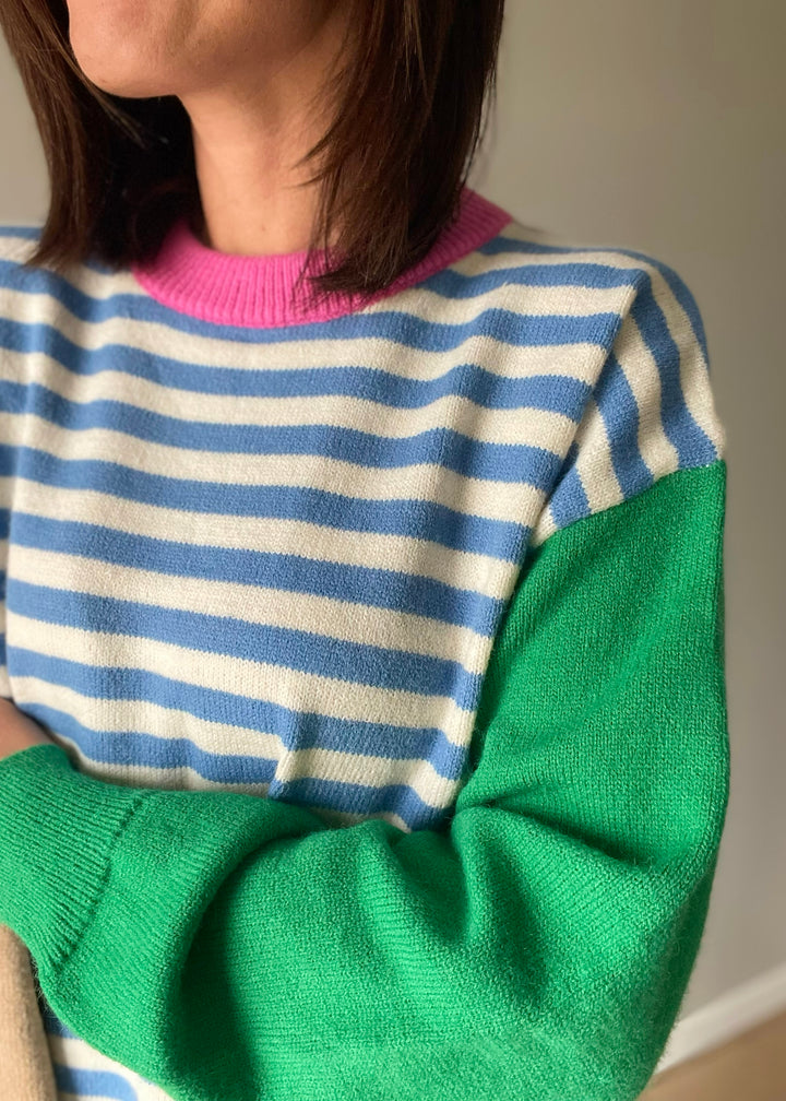 Women's color block sweater with blue stripes, pink collar, and green and tan sleeves.