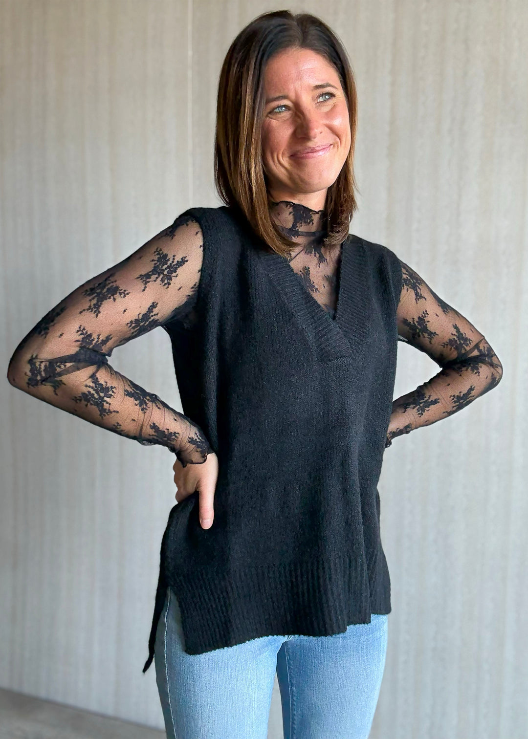 Women's Oversized Black Sweater Vest w/V-neck line paired over a sheer black lace long sleeve top.