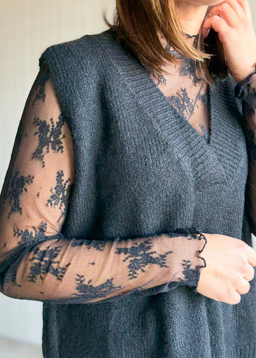 Women's Oversized Black Sweater Vest w/V-neck line paired over a sheer black lace long sleeve top.