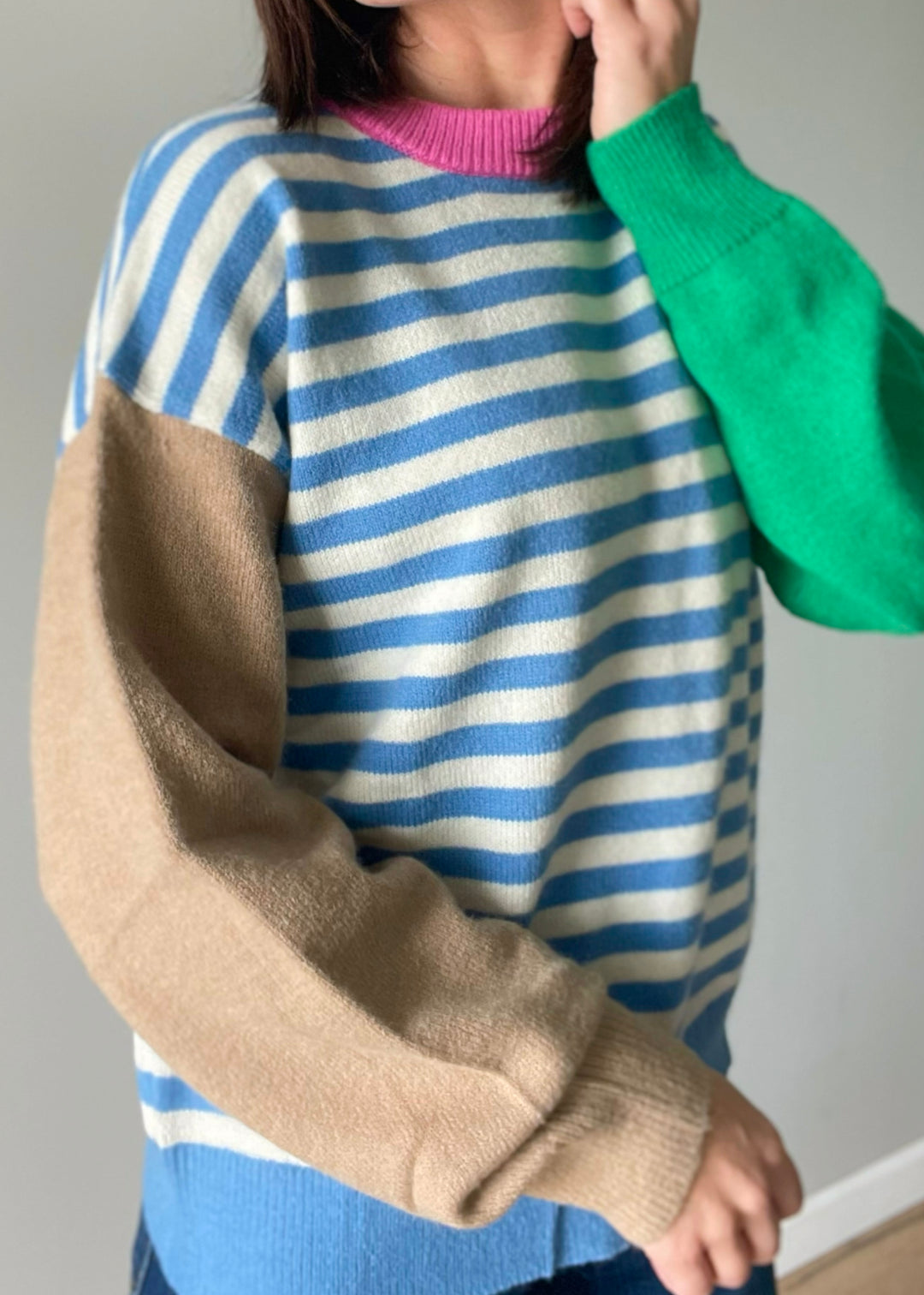 Women's color block sweater with blue stripes, pink collar, and green and tan sleeves.