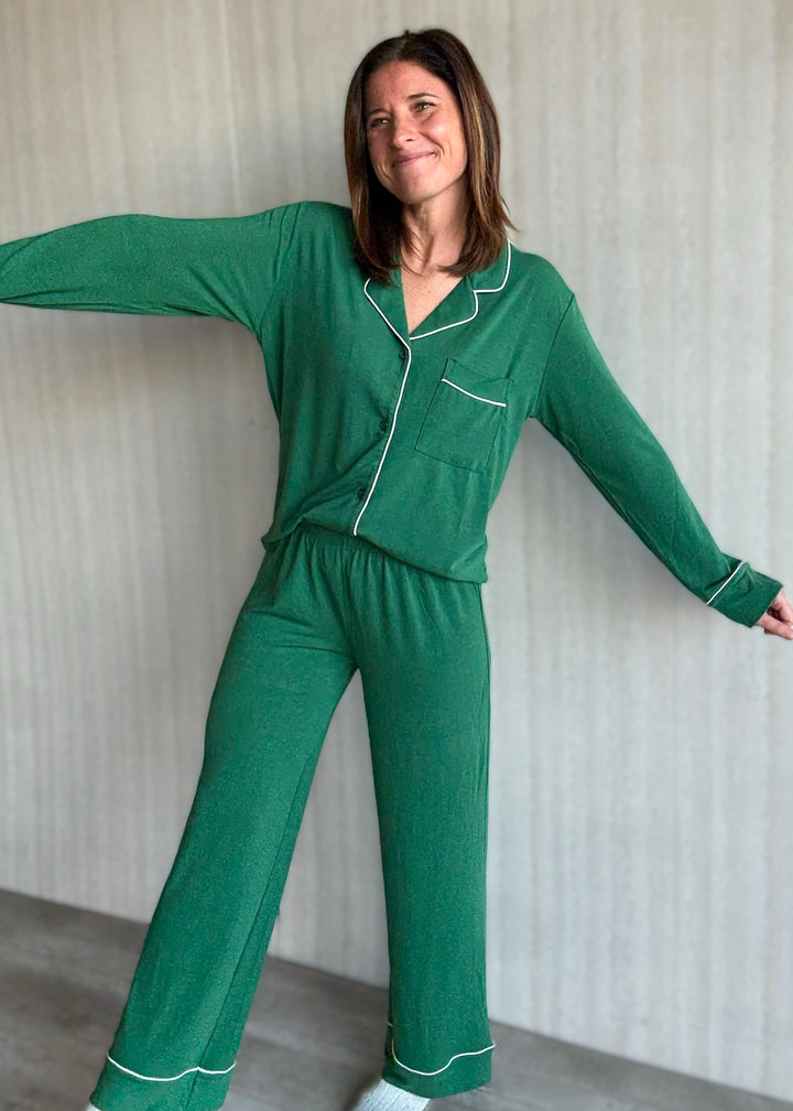 Woman wearing a green pajama set with white piping against a neutral background