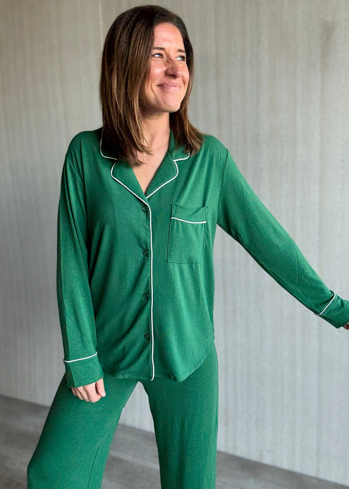 Woman wearing green pajamas with white piping in a neutral setting