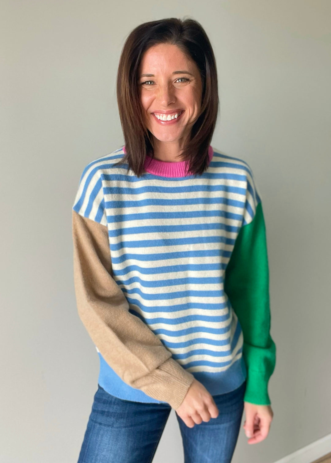 Women's color block sweater with blue stripes, pink collar, and green and tan sleeves.