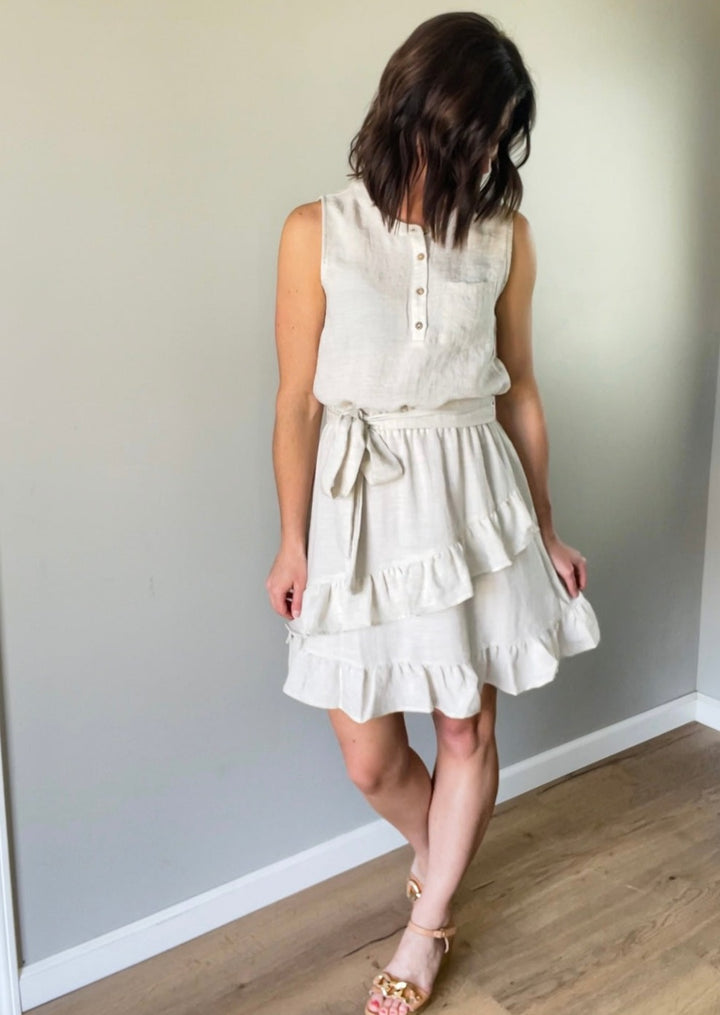 Light cream linen summer sleeveless dress with ruffle skirt and tie belt.