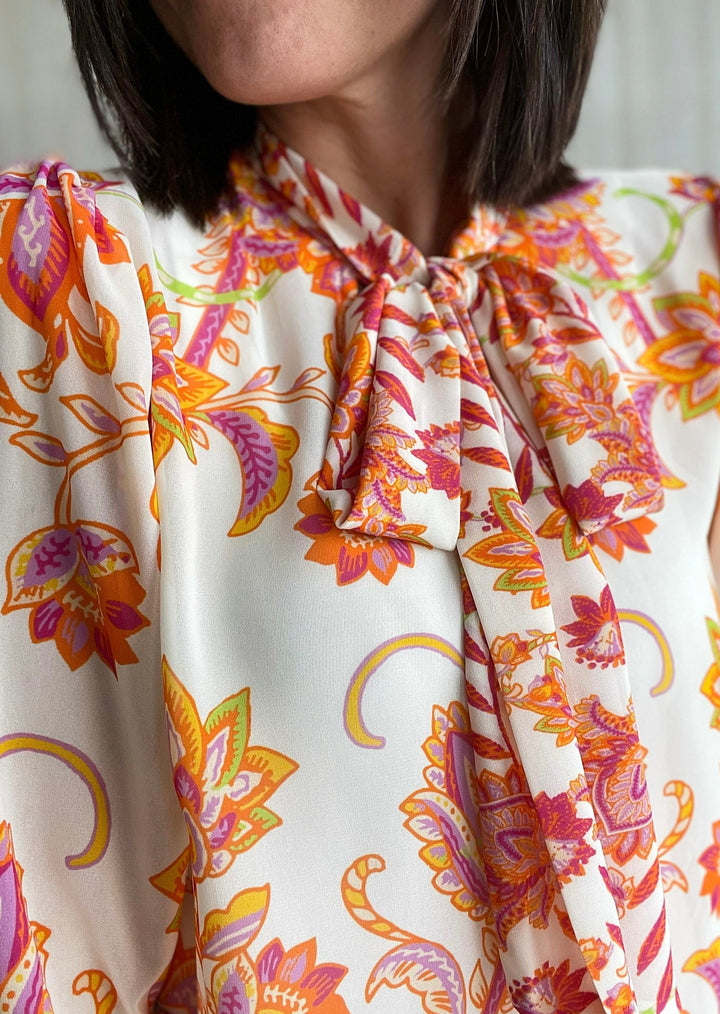 Ivory dress blouse with long sleeves and a printed design in purple, orange, pink, and green colors.