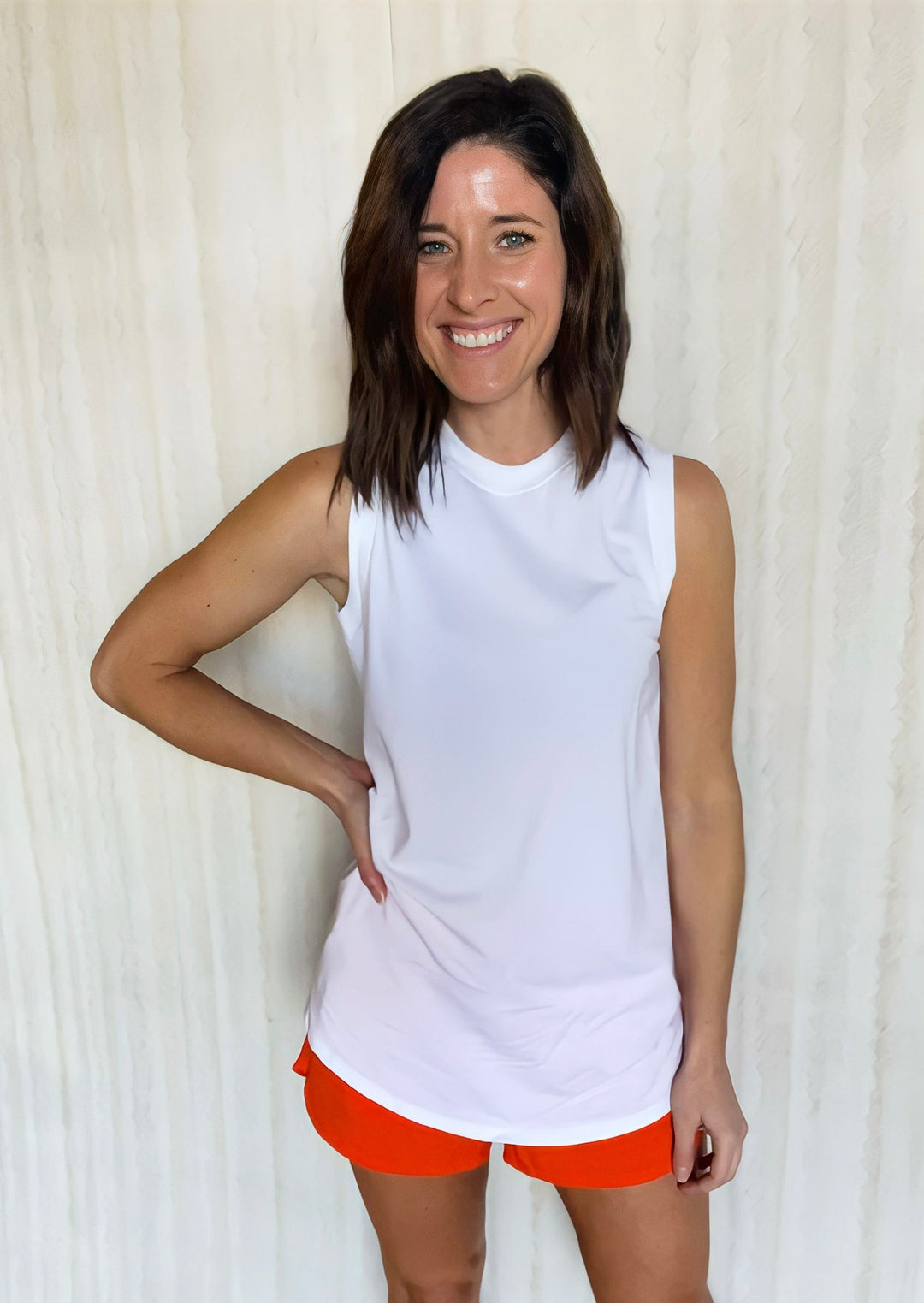 Women's White Tank Top paired with orange athleisure shorts.