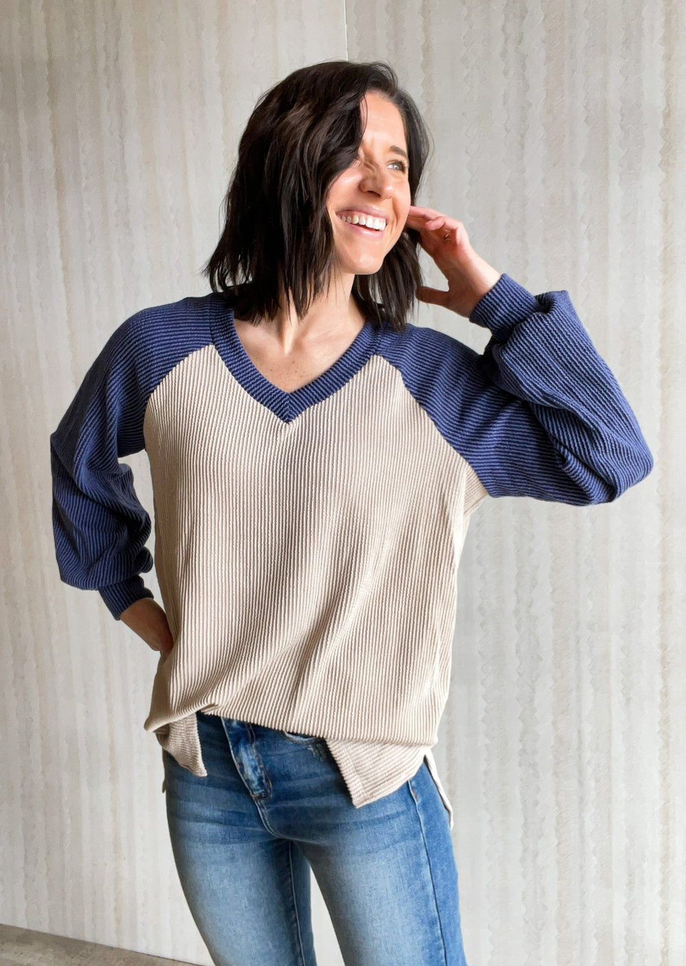 Navy and Taupe colorblock raglan texture top. An elevated spin on your typical baseball raglan, this long sleeve top features a v-neck, blue bishop sleeves, and a taupe colored relaxed fit body. Fabric is a lightweight urban rib knit.